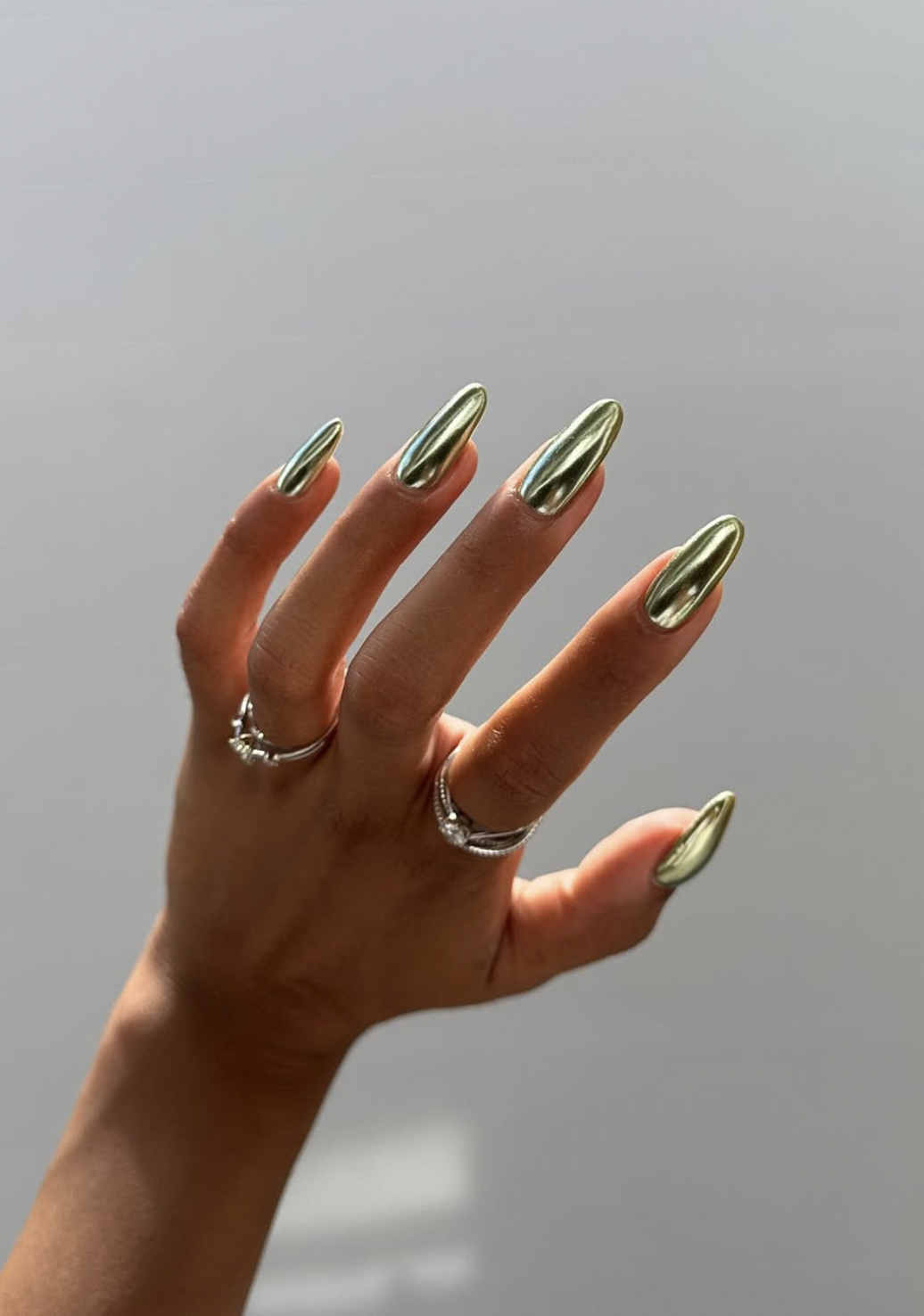 Sage green manicure with a soft pearlescent chrome finish.