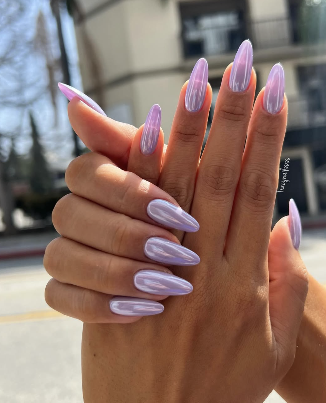 Long, almond-shaped nails showcasing an ethereal lavender purple base coat finished with a luminous, light-catching iridescent chrome glaze.