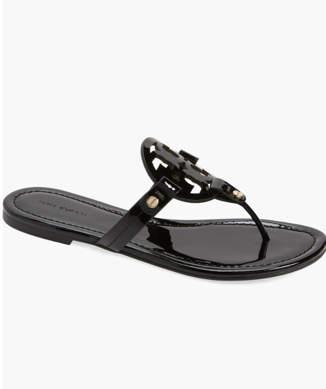 A pair of black leather Tory Burch Miller thong sandals featuring the signature laser-cut logo medallion and a slim flat sole.
