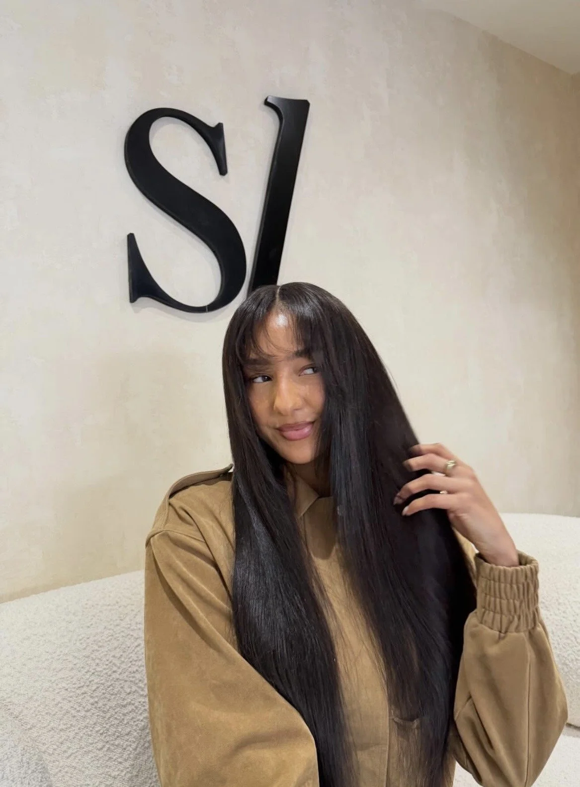 A woman with a square face shape wearing long straight hair with soft, wispy fringe bangs that help balance a strong jawline.