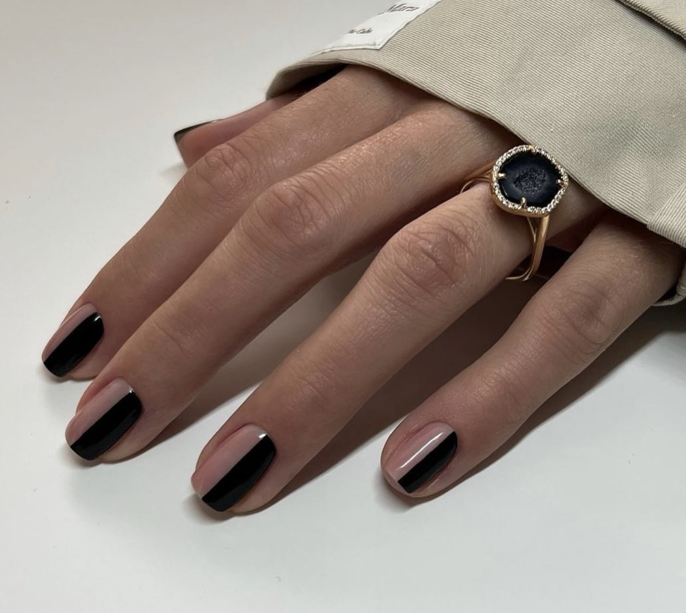 Almond-shaped nails featuring a high-gloss nude base with a wide, solid black French tip and a thick negative space band across the center of the nail bed.