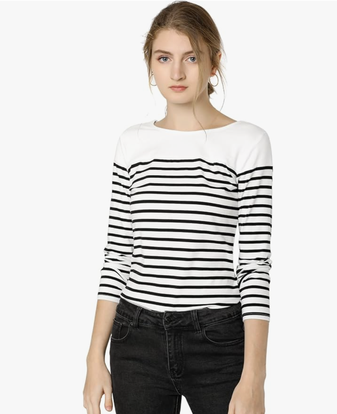 A woman wearing a white long-sleeve top with horizontal black stripes tucked into black jeans, showcasing a classic Breton stripe style.