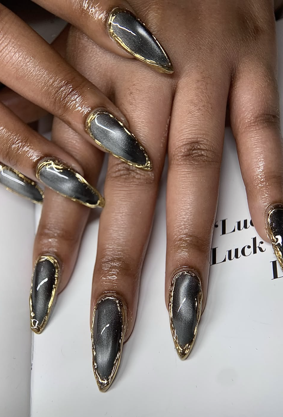 Black aura nails with tiny gold studs near the cuticles.