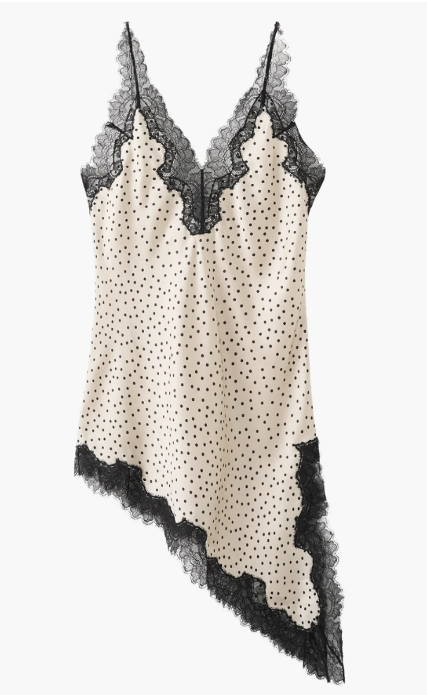A cream-colored satin camisole with black polka dots and an asymmetrical black lace hem, shown as a stylish top to wear with jeans.
