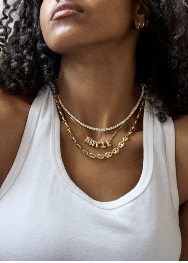 A person wearing a gold Baublebar Thalia Necklace, featuring a thick paperclip chain link design.