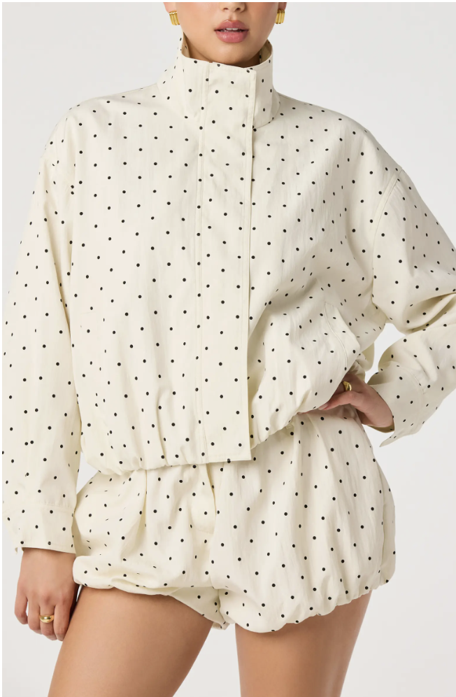 Cream-colored matching set featuring a long-sleeve polka dot bomber jacket with a large waist belt and coordinating high-waisted polka dot shorts.