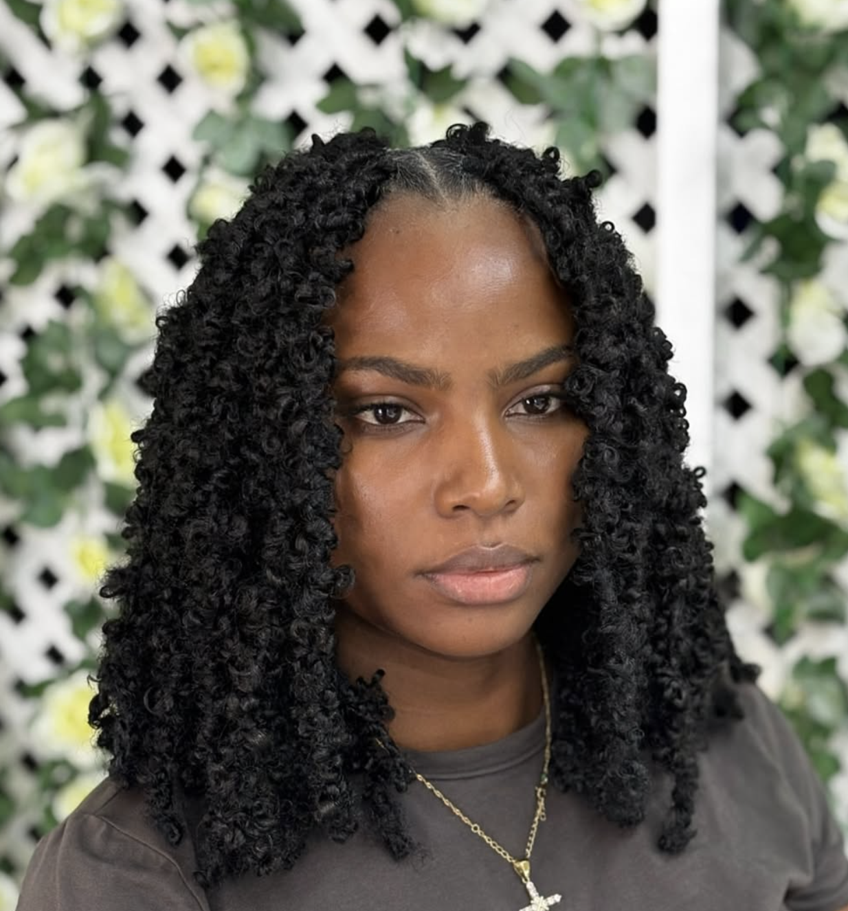 "A woman with a square face shape wearing voluminous, shoulder-length butterfly locs with a distressed texture that creates a soft, organic frame for the jawline.