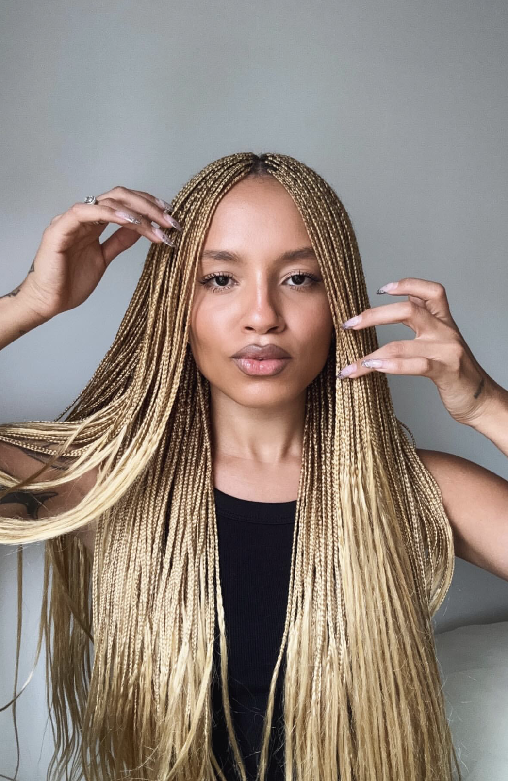 Woman wearing polished medium knotless braids styled over one shoulder for a braided hairstyle inspiration guide.