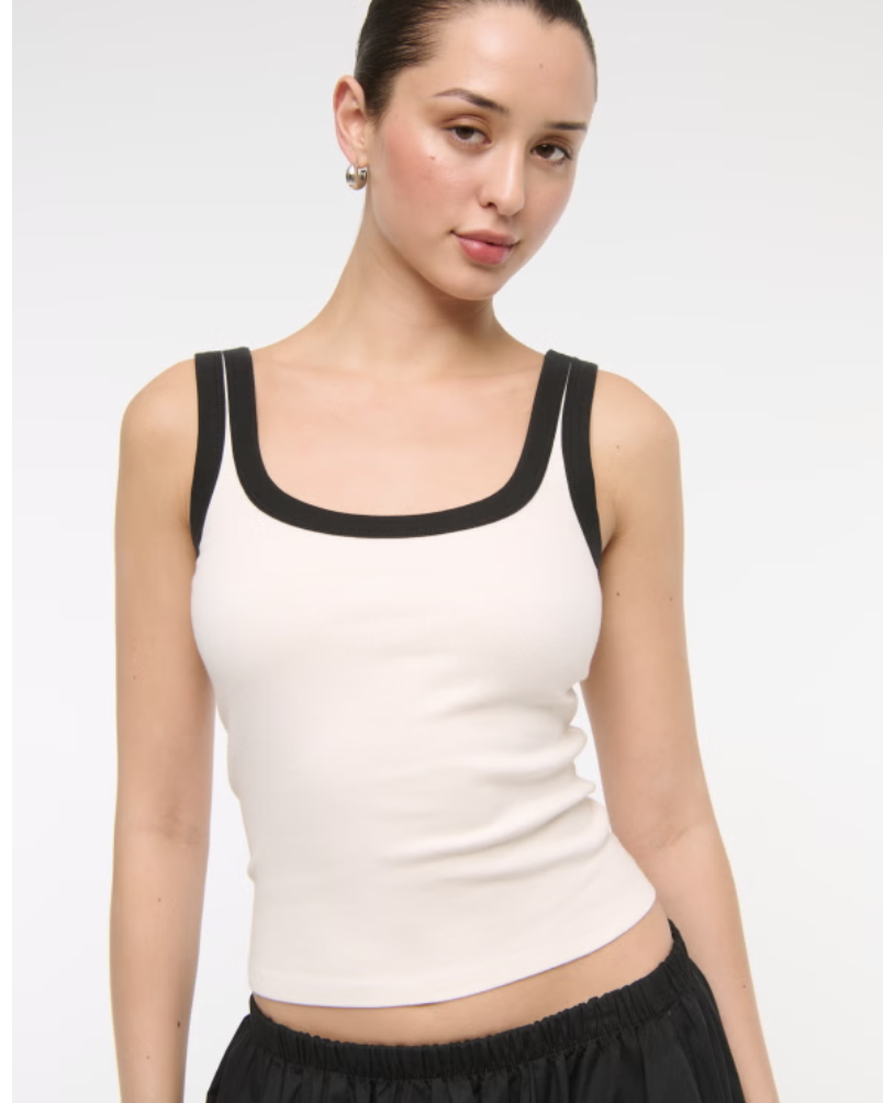 A woman wearing the Abercrombie Vintage-Style Rib Tuckable Scoopneck Tank in white with black trim.