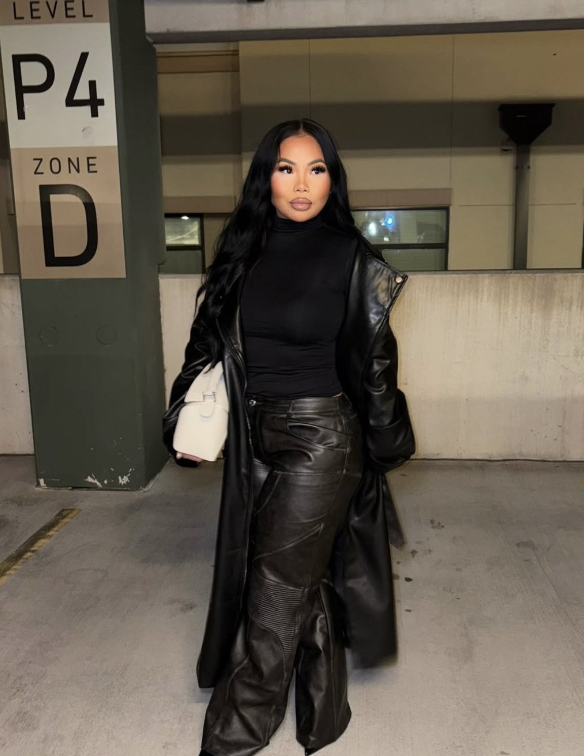 Woman wearing an all-black outfit with wide-leg leather pants, black turtleneck and a long leather trench coat