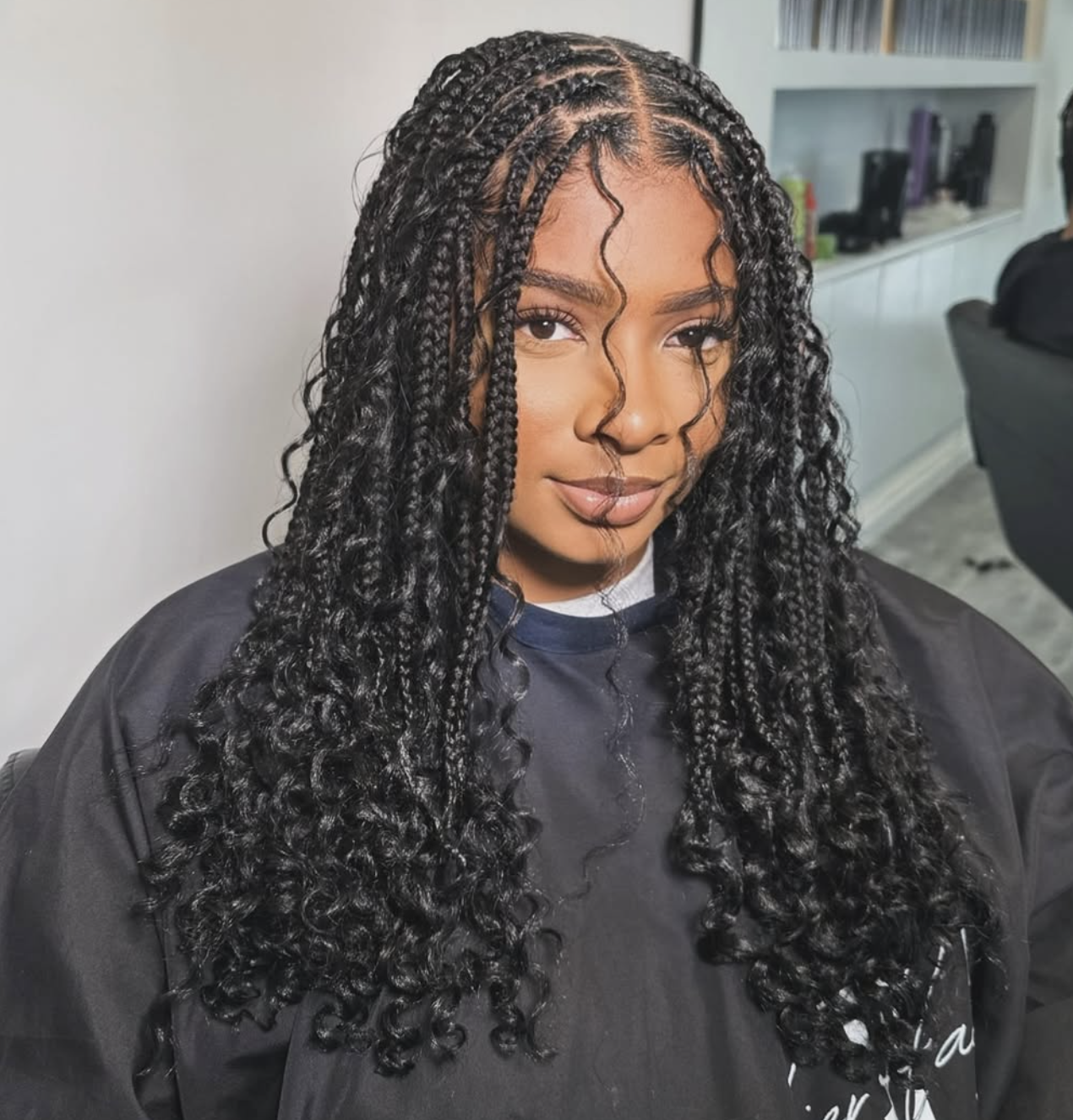 Woman wearing medium knotless box braids with a clean center part and natural-looking roots.