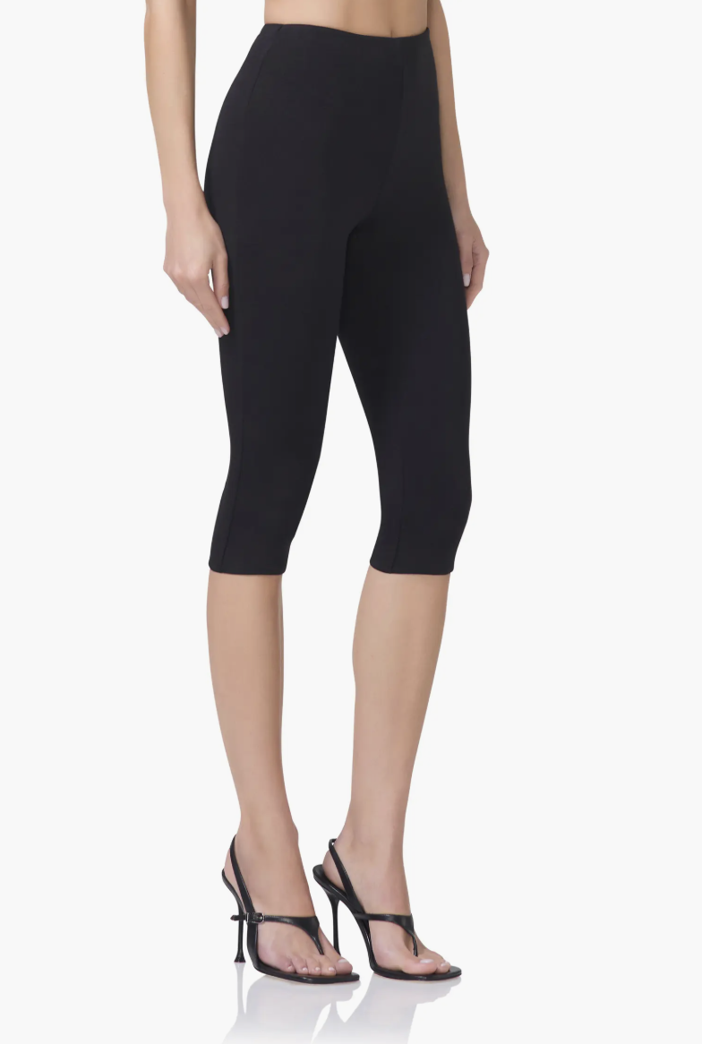 A close-up of a woman's legs wearing the black AFRM Ettie High Waist Capri Pants paired with black strappy stiletto sandals.