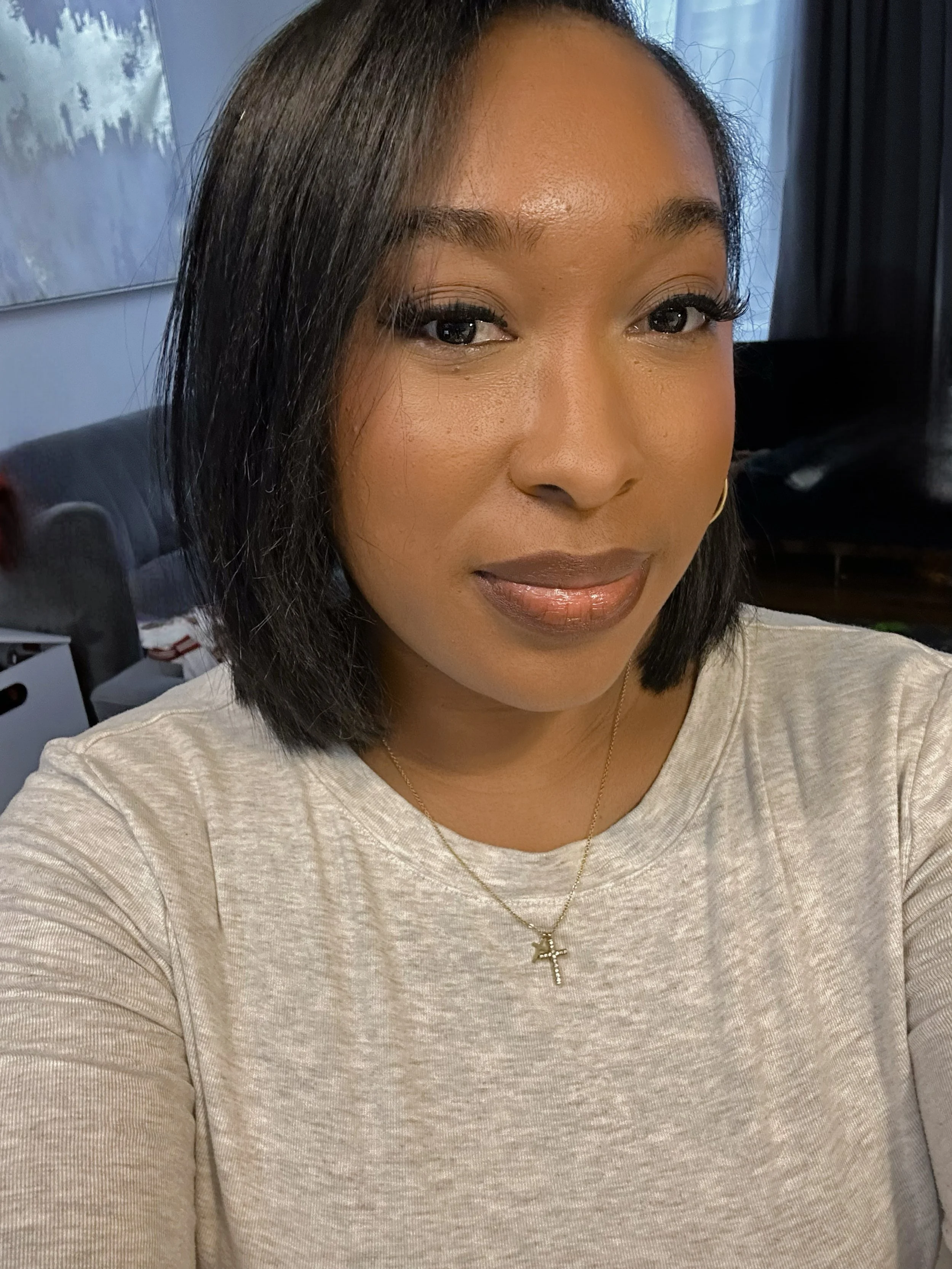 Close-up portrait of a woman showcasing a sleek, bone-straight professional silk press on her dark hair, styled into a sharp, shoulder-length blunt bob with a side part.