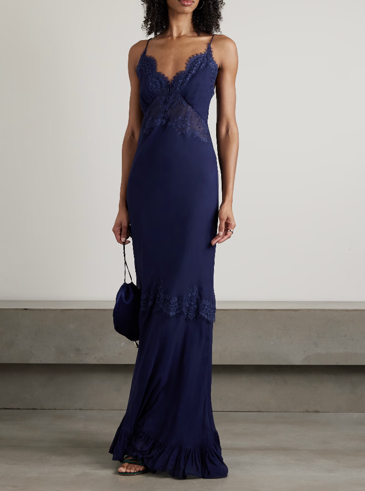A woman wearing a navy Self-Portrait lace-trimmed georgette maxi dress with delicate lace inserts, a romantic choice for a luxury spring wedding guest.