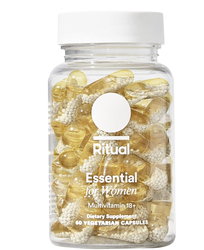 A clear product shot of a bottle of Ritual Essential for Women 18+ daily multivitamins, showcasing the clear beadlet-in-oil capsules filled with key nutrients against a transparent background.