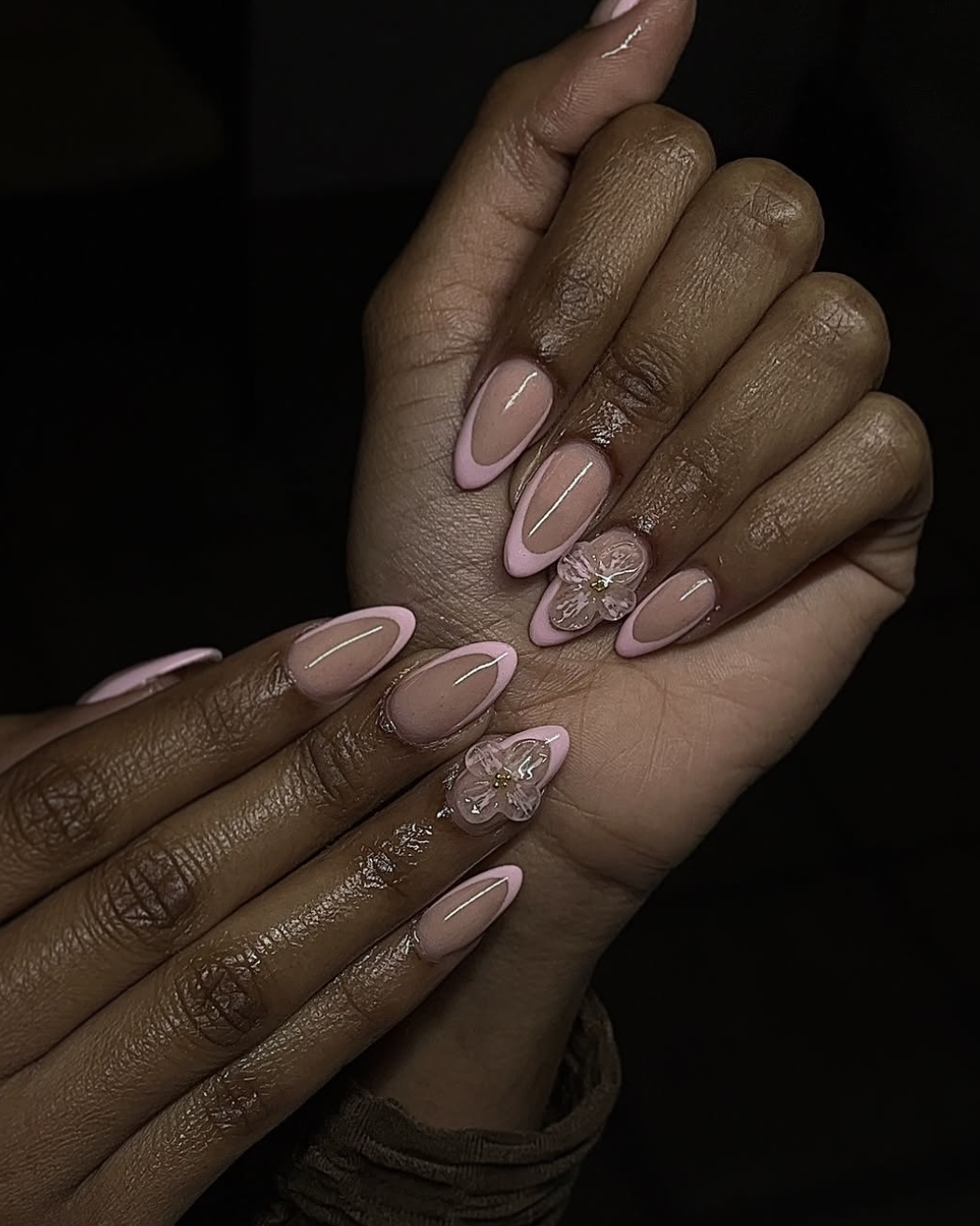 Long almond-shaped nails with a nude-pink base featuring 3D clear gel flower sculptures and pink French tips.