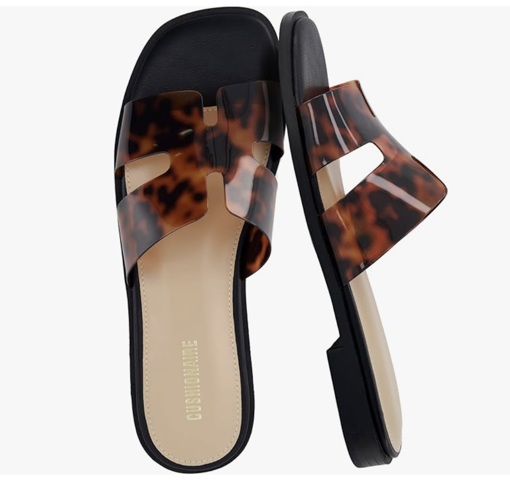 A pair of tortoiseshell patterned slide sandals with a geometric cutout strap design, a stylish and comfortable shoe to wear with white wide-leg jeans.