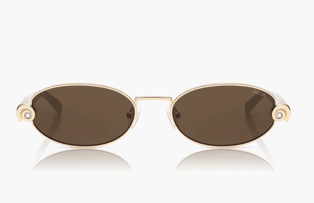A pair of SOJOS Oceanus Lovelace oval sunglasses featuring brown tinted lenses and a slim gold metal frame with a small circular crystal detail on the temple.
