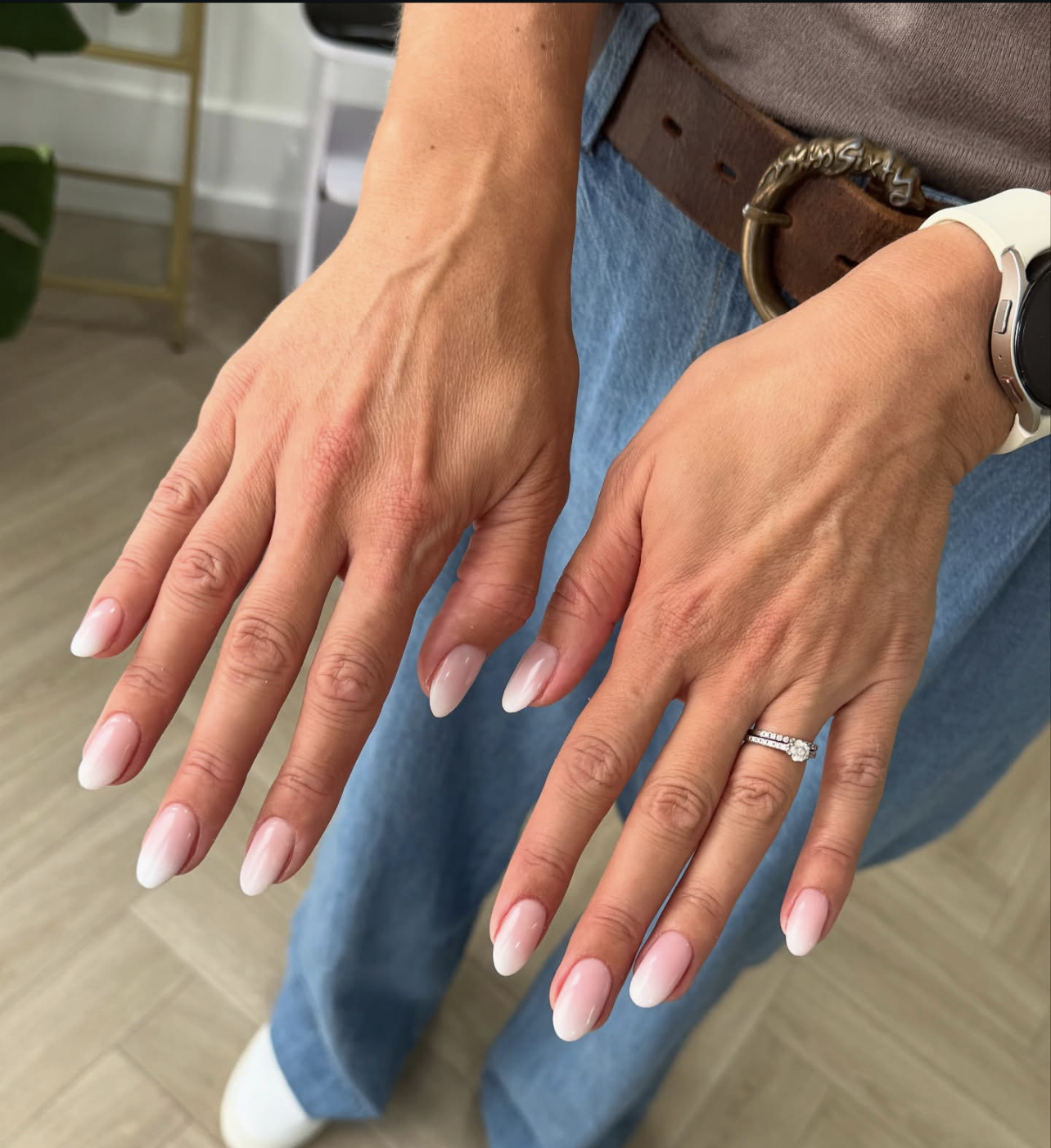 A close-up of long almond-shaped gel nails featuring a soft gradient from nude to white in a classic French ombre style.