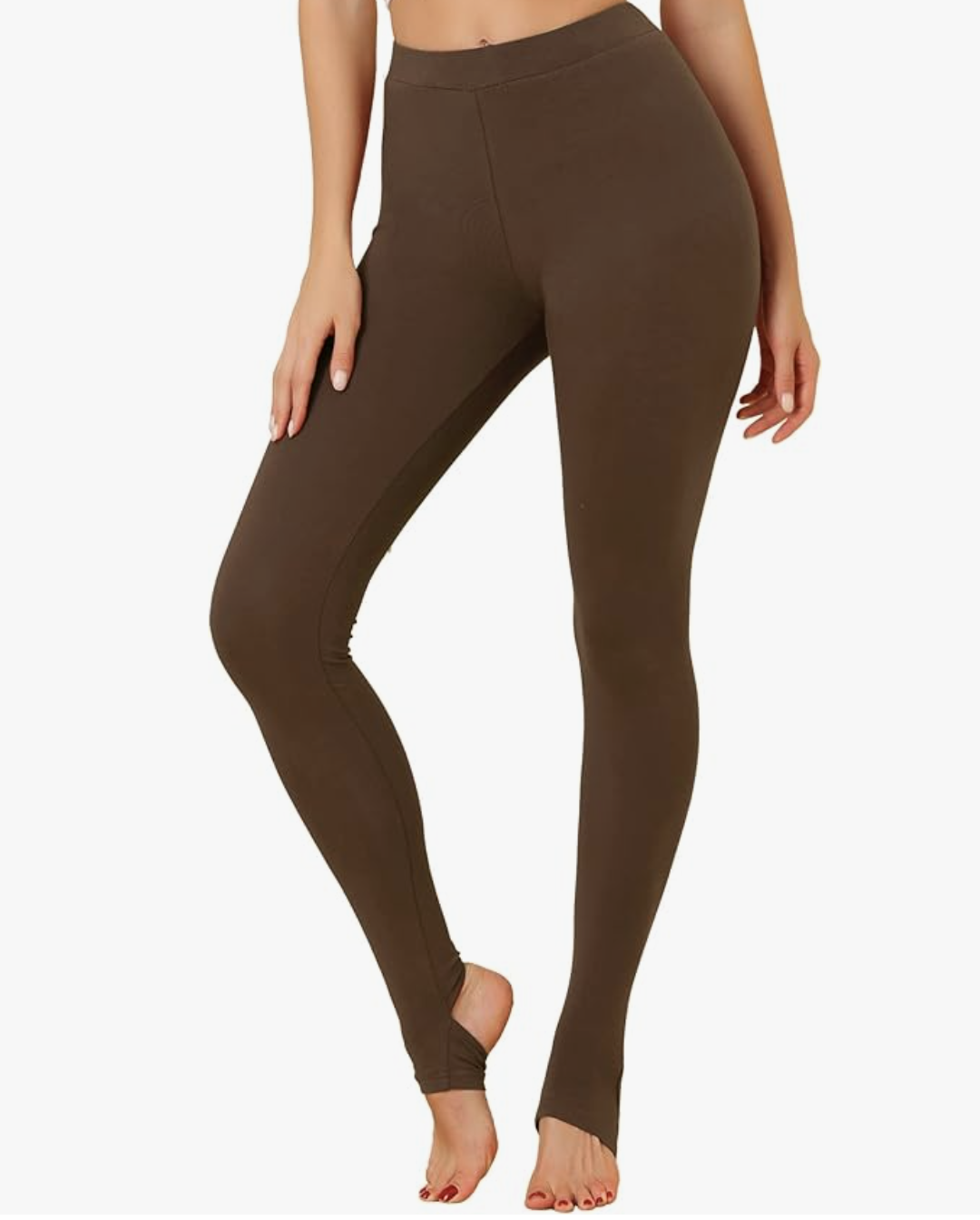 Close-up of a person's feet wearing brown cotton stirrup leggings with the elastic strap looped under the arch of the foot.