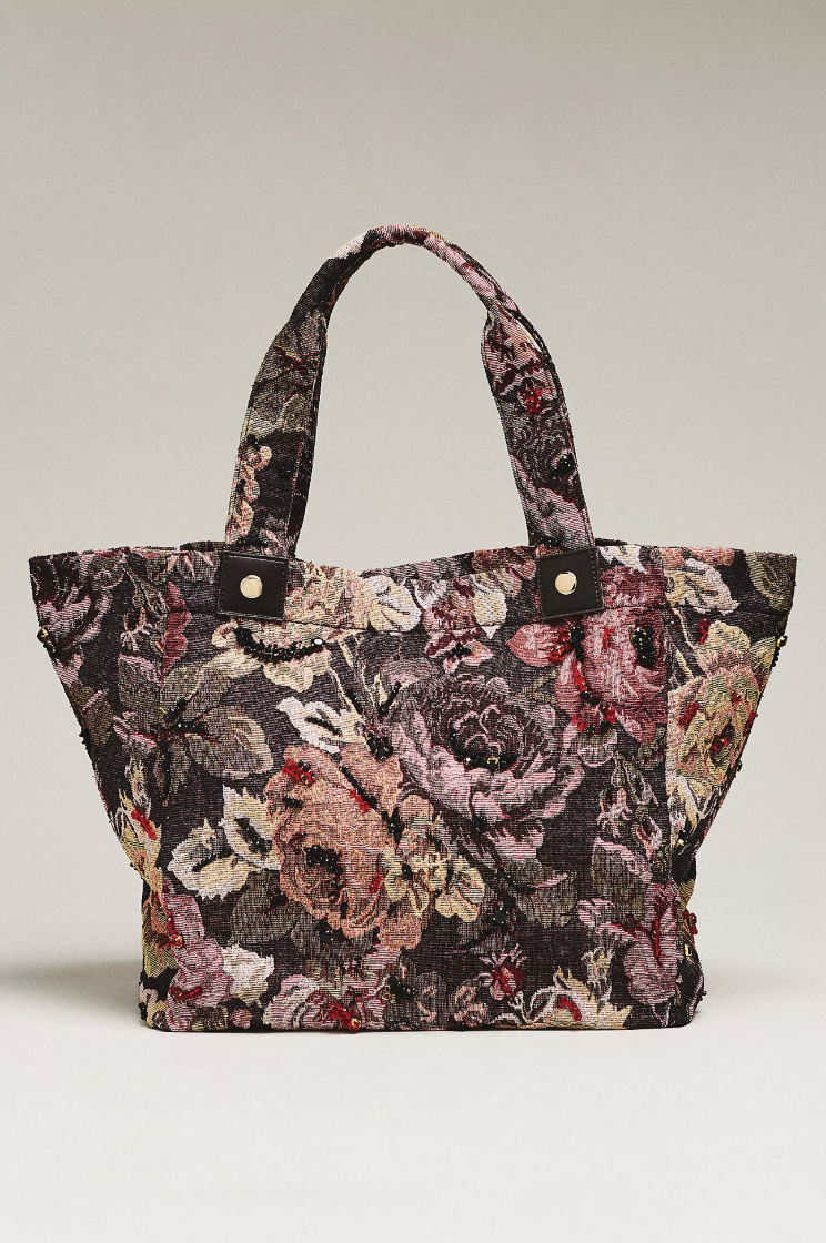 Floral tapestry tote styled with straight-leg jeans, a cream sweater and a long coat.