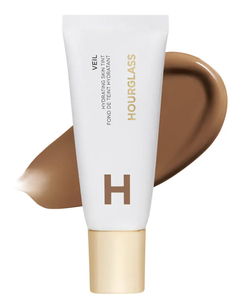 A tube of Hourglass Illusion Hyaluronic Skin Tint with a smooth swatch of hydrating liquid foundation spread behind it.