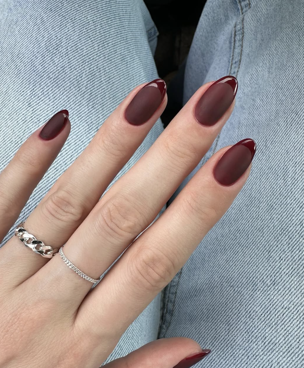 Close-up of burgundy reverse french on neatly manicured hands