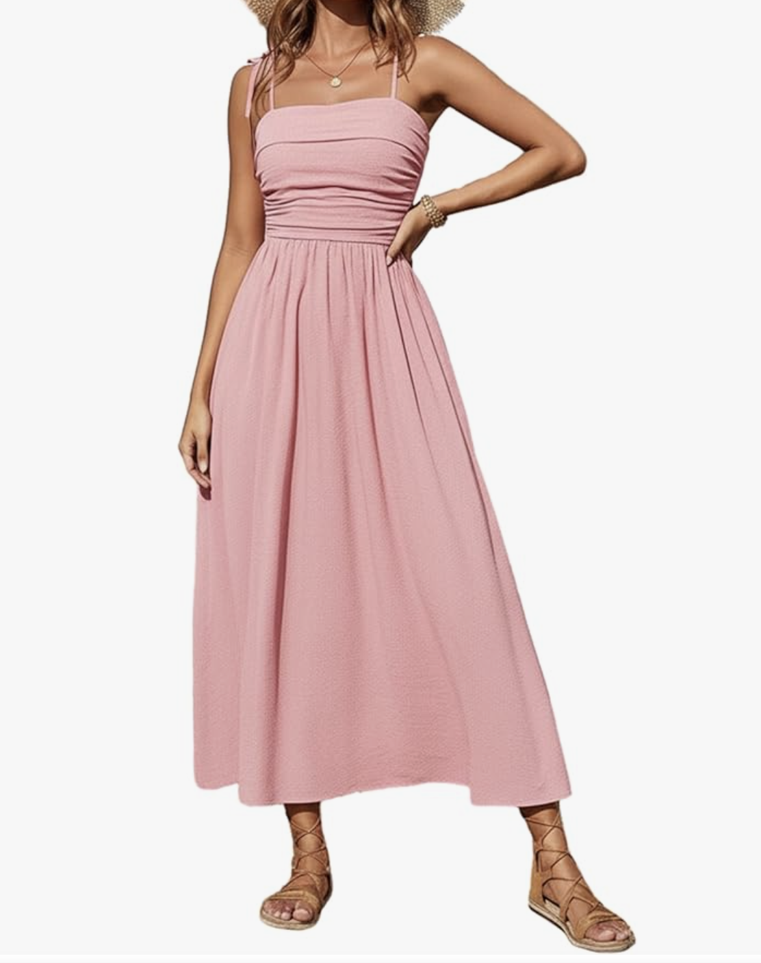 A woman wearing a pink smocked spaghetti strap maxi dress with brown gladiator sandals, showing a summer outfit idea for what to wear with a spaghetti strap dress.
