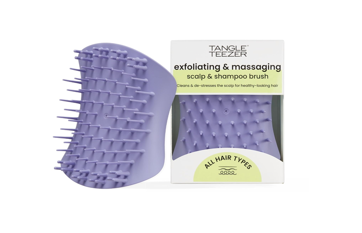 A purple Tangle Teezer Scalp Exfoliator and Massage Brush next to its packaging, featuring a two-tier teeth design to lift buildup and flakes from the scalp.