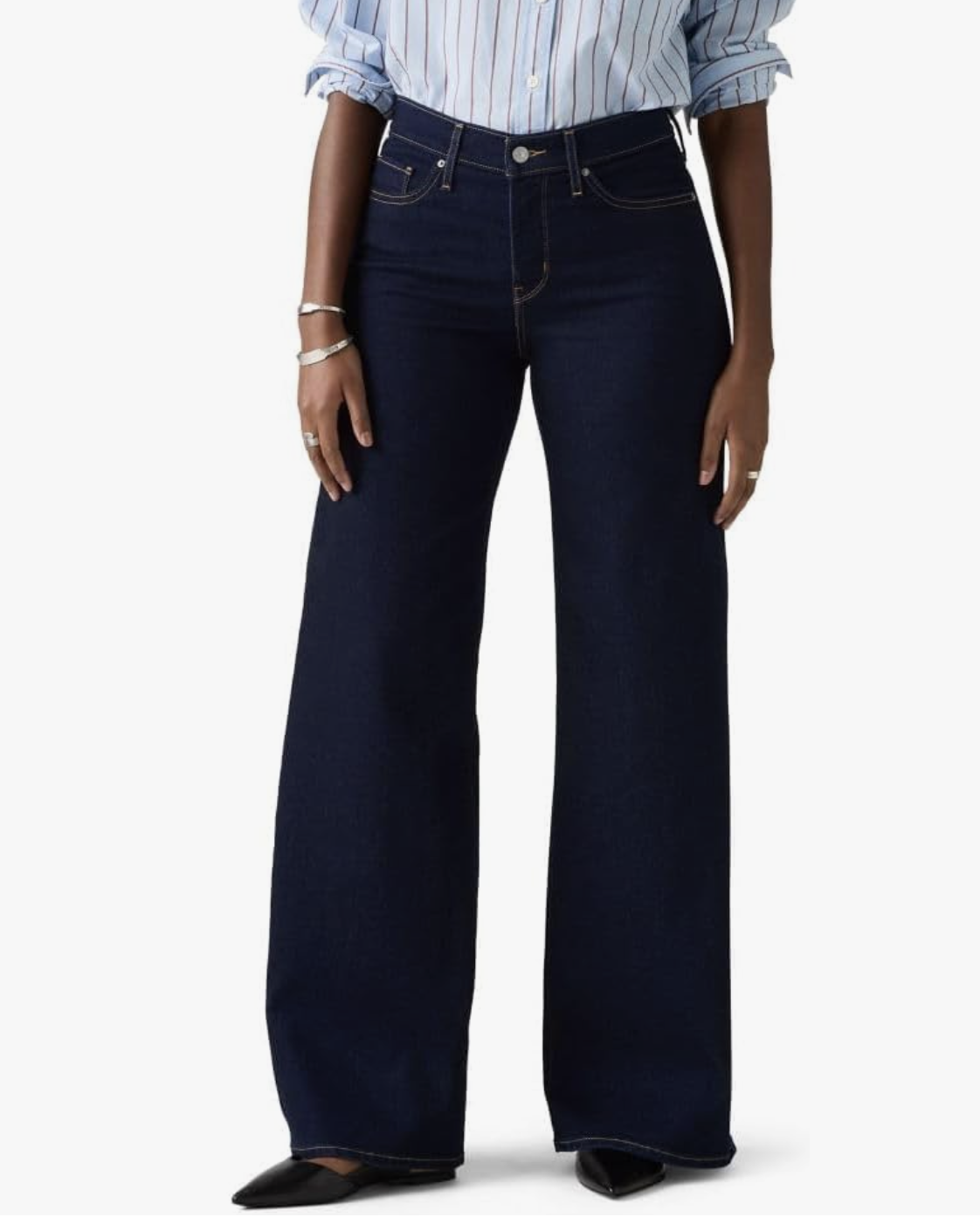 A close-up of a person wearing Levi's 318 Shaping Wide Leg jeans in a dark indigo wash, paired with black pointed-toe flats.