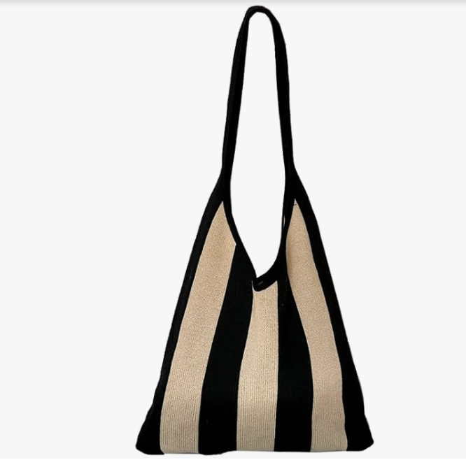 A close-up of a slouchy, lightweight knit tote bag featuring thick vertical black and tan stripes with a matching shoulder strap.