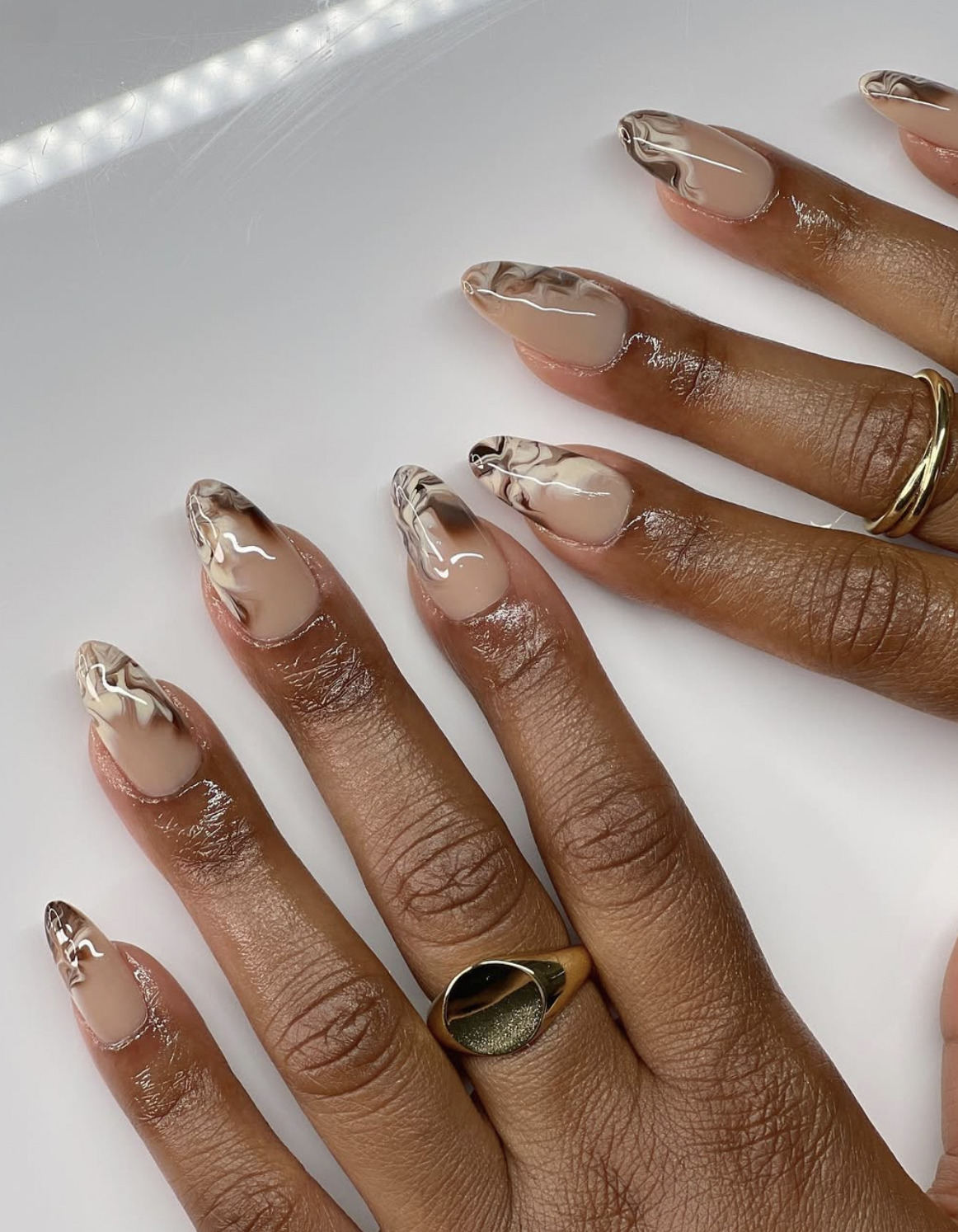 caramel nude french tips manicure photographed close up on hands.