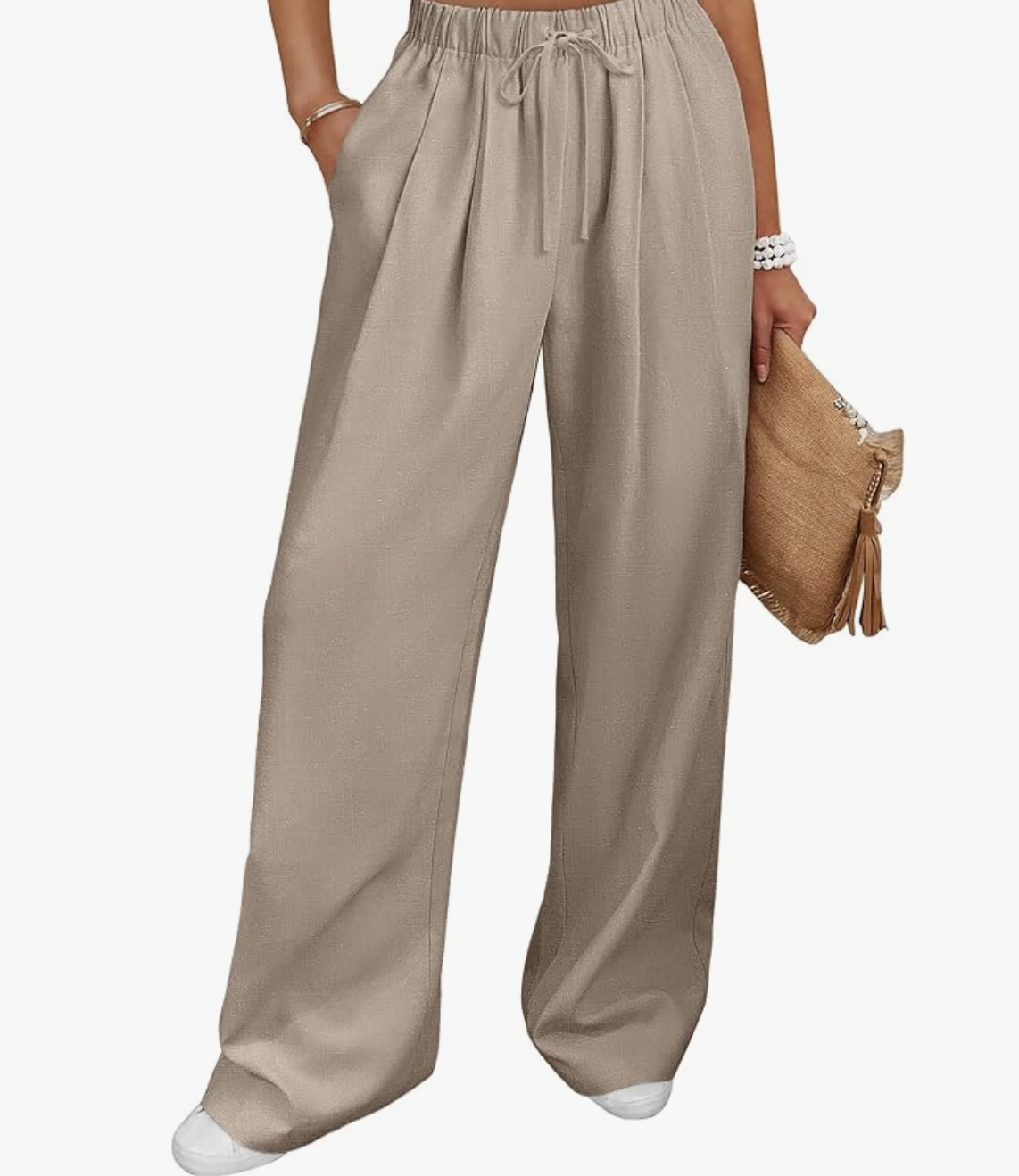 Relaxed-fit neutral wide-leg linen pants paired with white shoes, showing a close-up of the flowing silhouette and draped fabric.