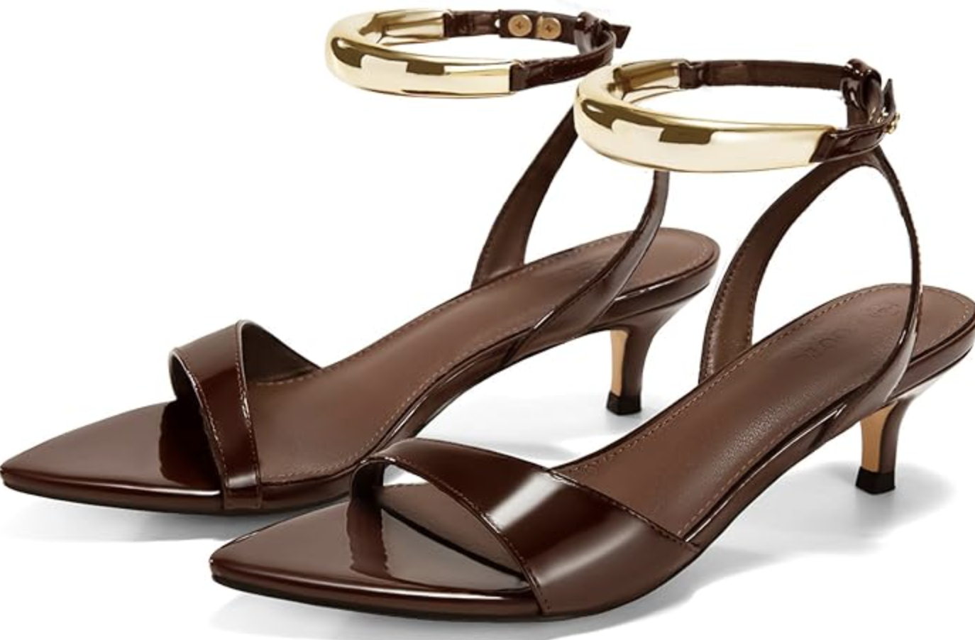 A pair of dark brown patent leather open-toe kitten heel sandals featuring a bold gold metallic ankle strap, a chic and professional footwear option for a 2026 office capsule wardrobe.