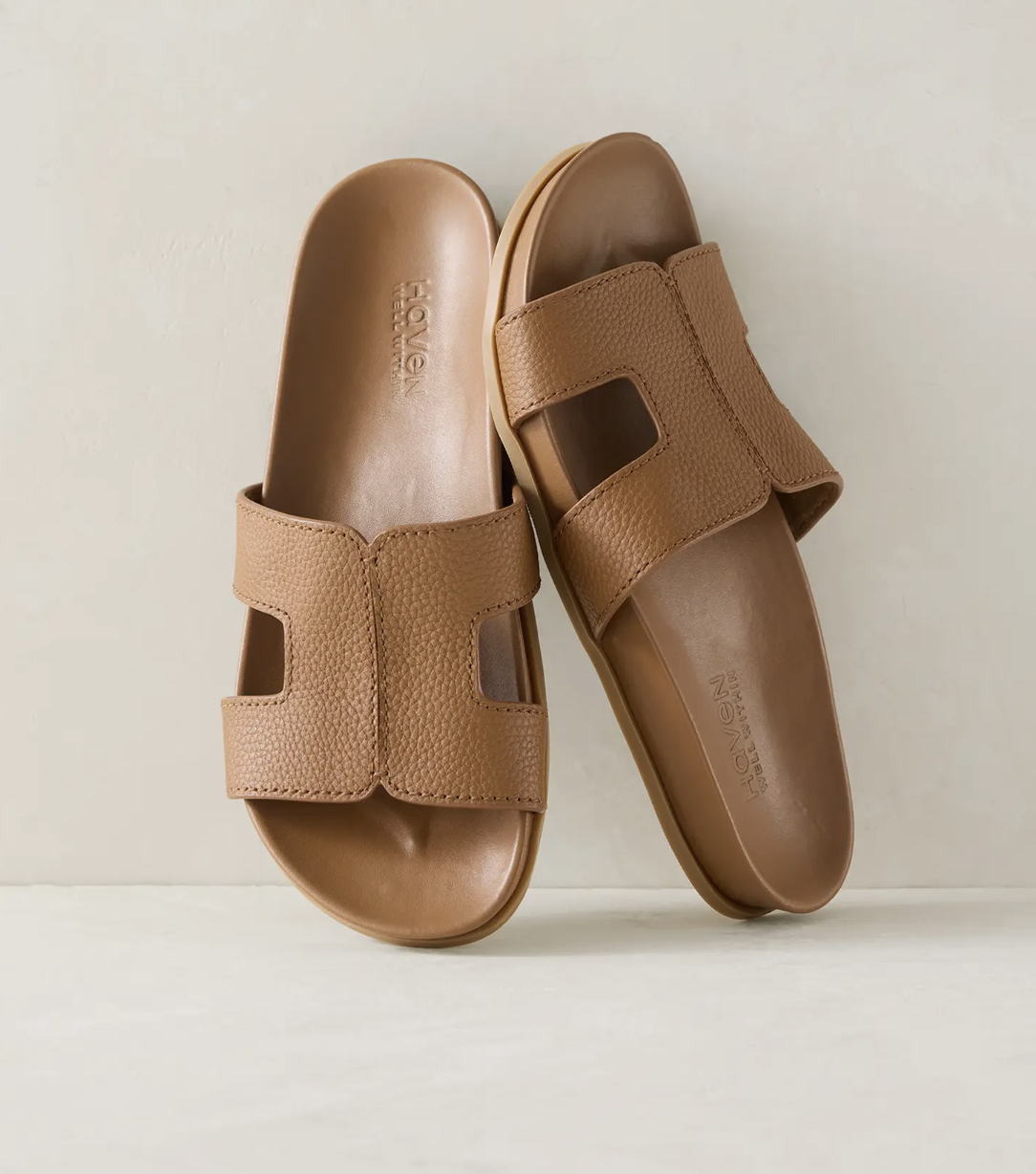 A pair of tan leather cutout slide sandals from Haven Well Within, featuring a wide H-shaped strap and a contoured comfort footbed.