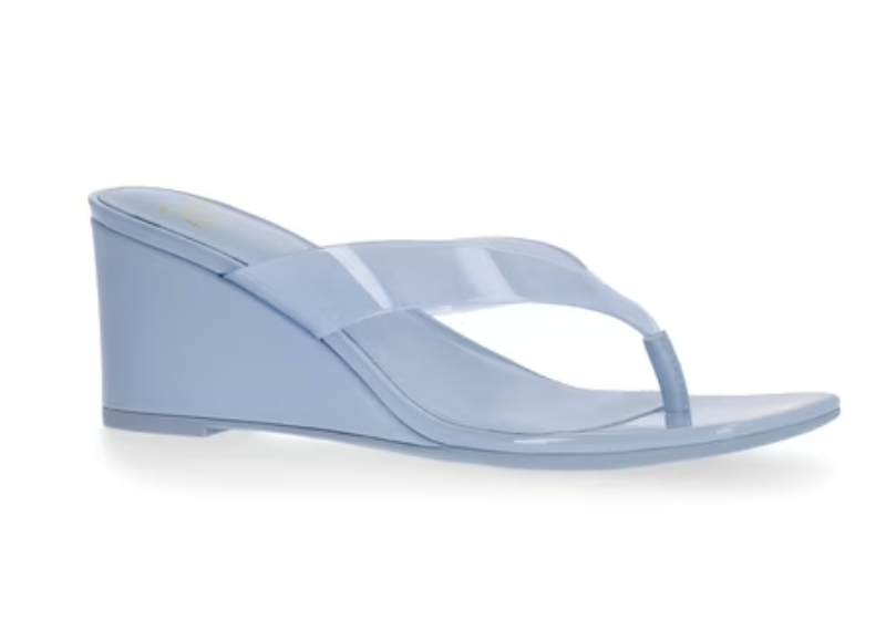 A side profile product shot of a trendy pair of clear light blue jelly wedge sandals featuring wide translucent straps, an open thong toe design, and a chunky matching blue wedge heel.