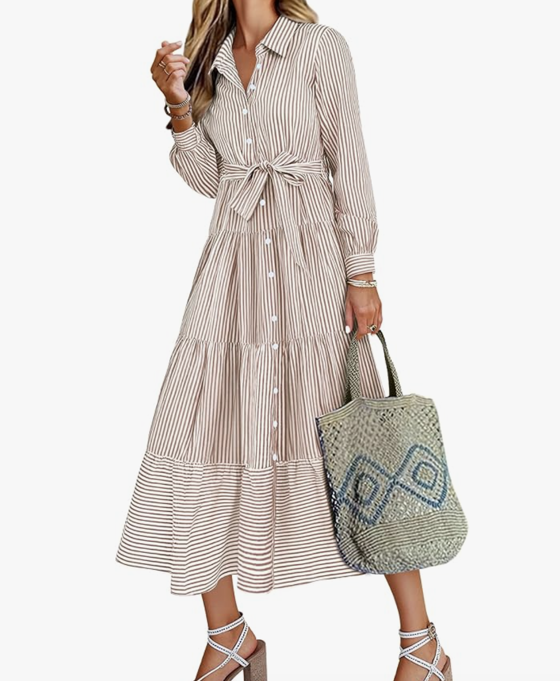A woman wearing a beige and white striped long-sleeve maxi shirt dress with a button-down front, belted waist, and a side slit.