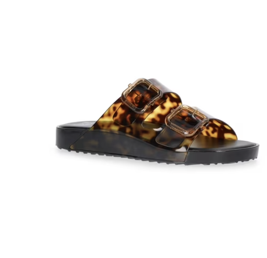 A product shot of trendy tortoiseshell print double-strap slide sandals featuring large matching buckles and a contoured black footbed.
