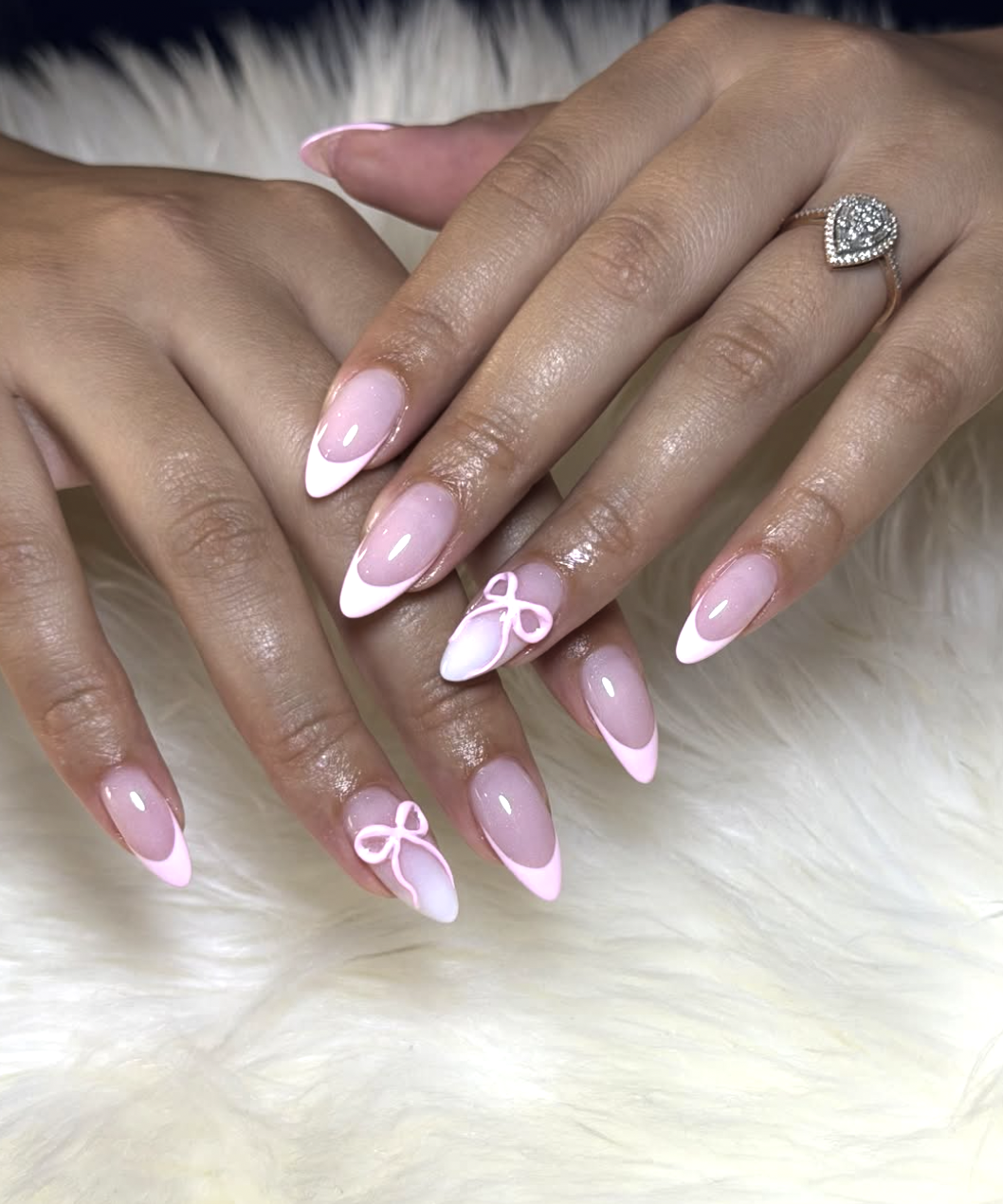High-feminine almond nails by @justfabbeautystudio featuring a soft pink French tip and delicate white 3D resin bow charms on the accent nails.