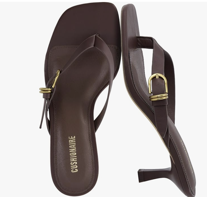 A pair of dark brown Cushionaire thong kitten heel sandals featuring a minimalist T-strap design and gold hardware, a perfect summer-to-fall transition shoe for a 2026 capsule wardrobe.