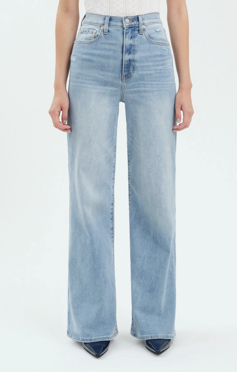 A product shot of light-wash DAZE Farout Wide Leg Jeans paired with dark pointed-toe boots, illustrating a fashion editor-approved way to balance high-volume denim with a sharp footwear silhouette.