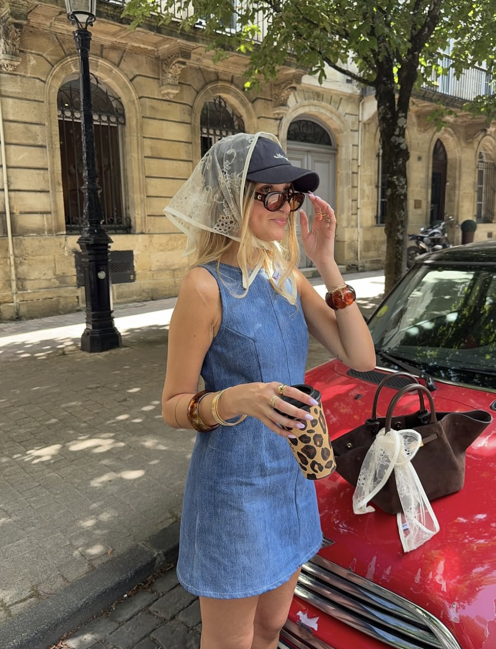 A woman wearing a button-down denim dress and classic white sneakers with a retro silhouette.
