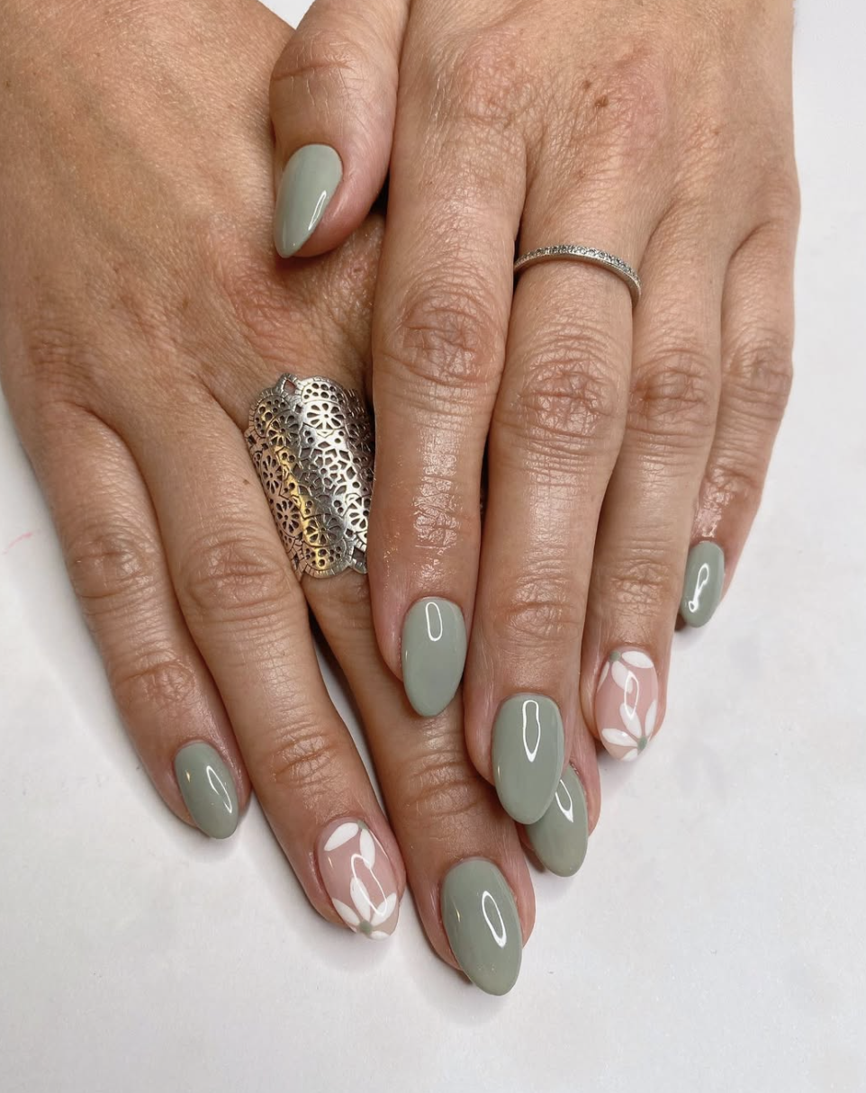 A close-up of almond-shaped nails with a sheer nude base and wavy, abstract mint green paint strokes across each nail.