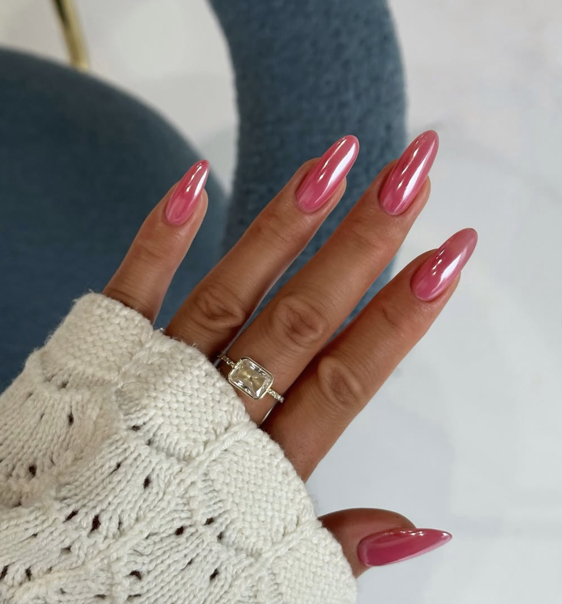 Long almond-shaped gel nails with a sheer, high-shine strawberry pink chrome finish.