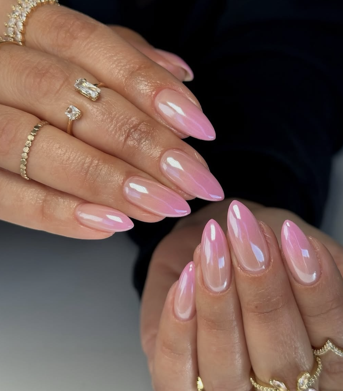 A close-up of almond-shaped nails with a warm peach-pink base and a shimmering iridescent chrome finish.