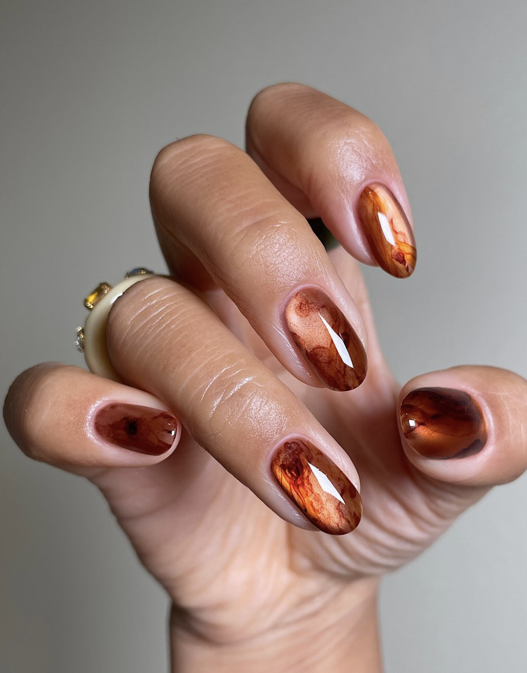 Close-up of short nails featuring a glossy burnished copper metallic manicure.