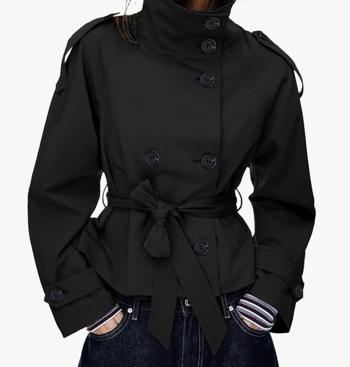Woman wearing a black cropped trench coat with wide sleeves and a belt, styled with a black headband and sunglasses while crouching outdoors.