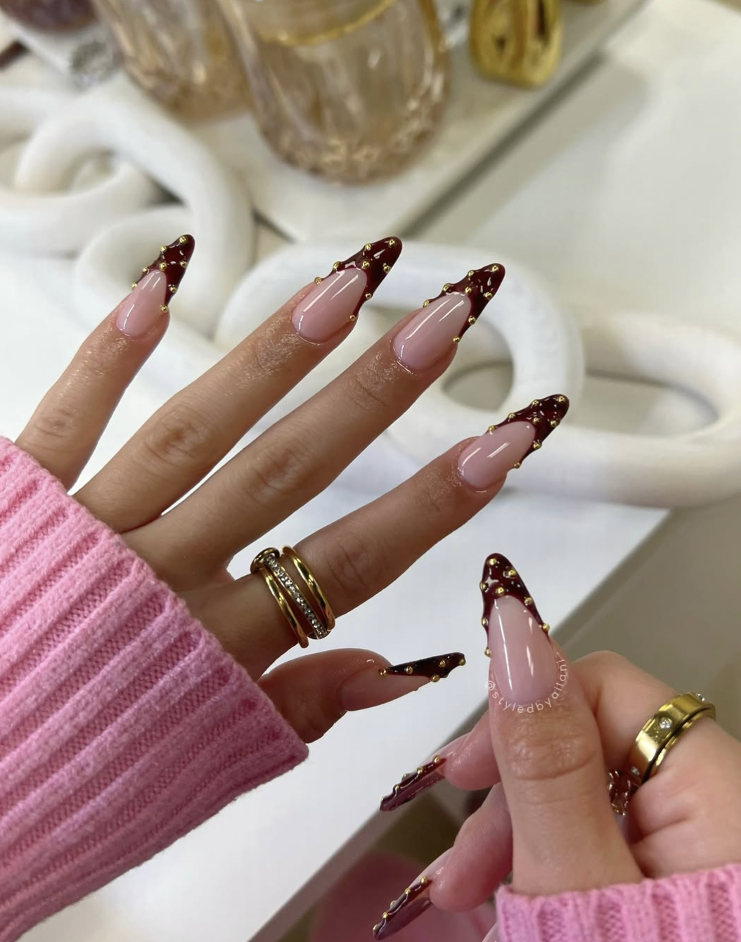 Almond-shaped gel nails with a neutral base, metallic gold foil accents, and 3D gold texture details.