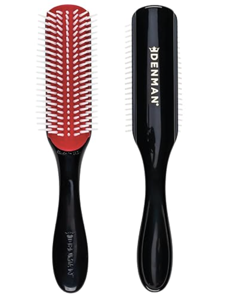 A Denman D3 Original Styler 7-row hair brush with a signature red pad and white nylon pins next to a black gloss handle.