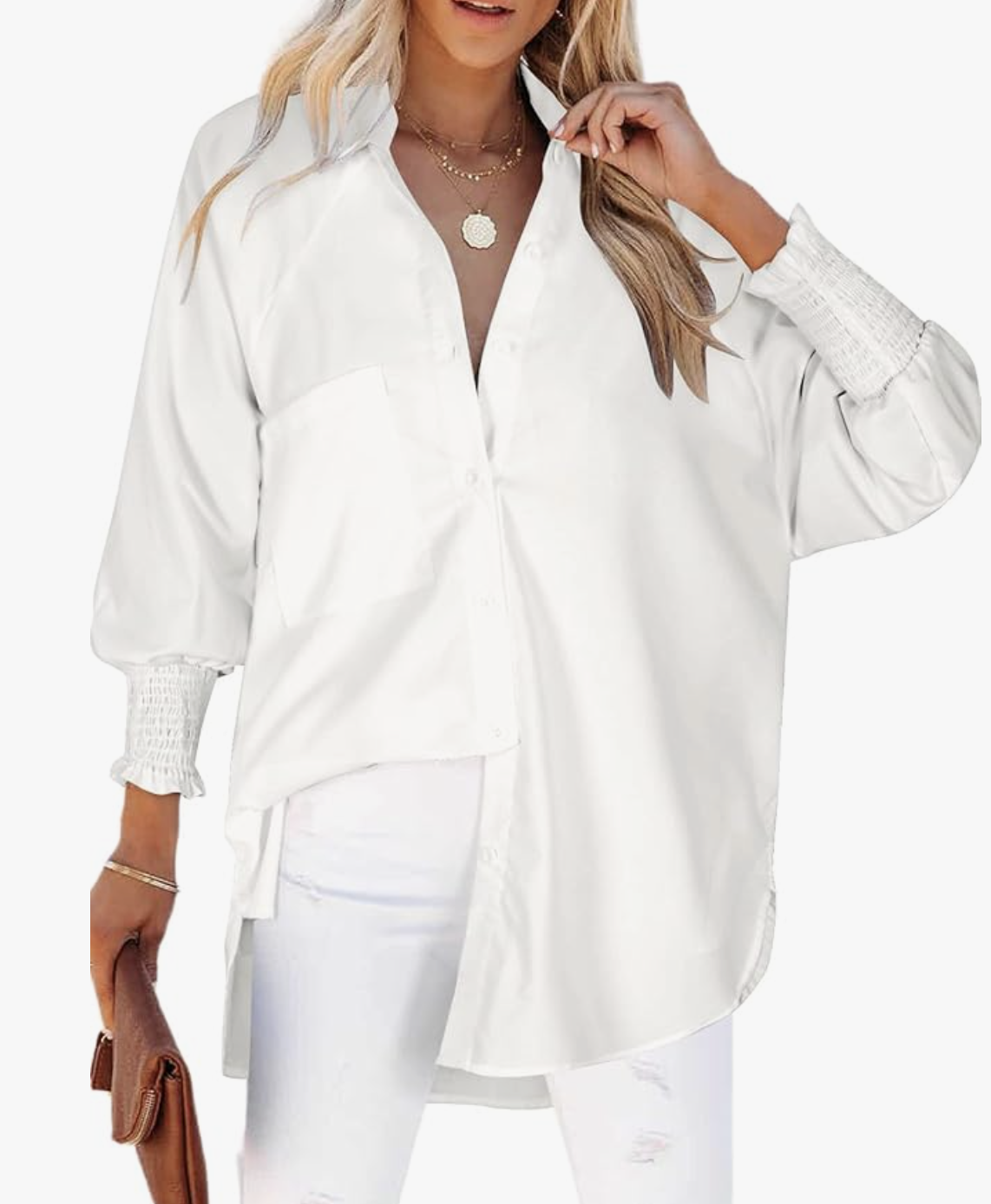 A woman wearing an oversized white cotton gauze button-down shirt with smocked cuffs, paired with white distressed jeans and a brown leather clutch.